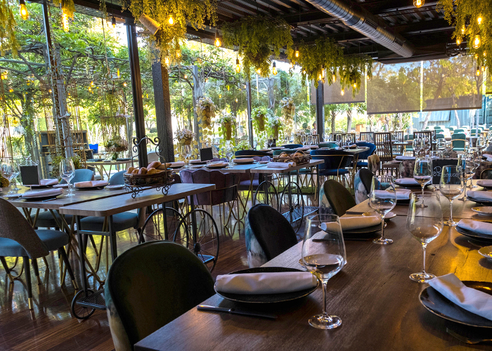 Comedor interior acristalado con vistas al jardín y plantas colgantes