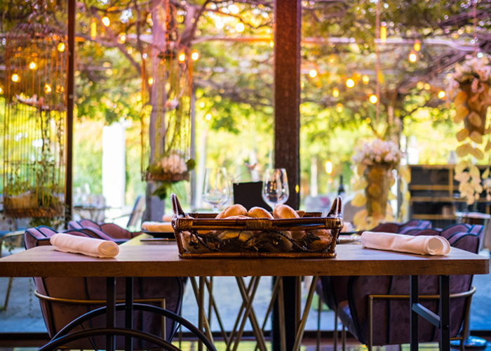 Mesa de madera con cesta de pan y luces cálidas junto al jardín