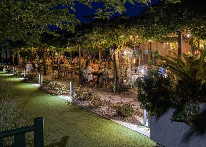 Terraza del restaurante de noche con guirnaldas de luces entre la vegetación