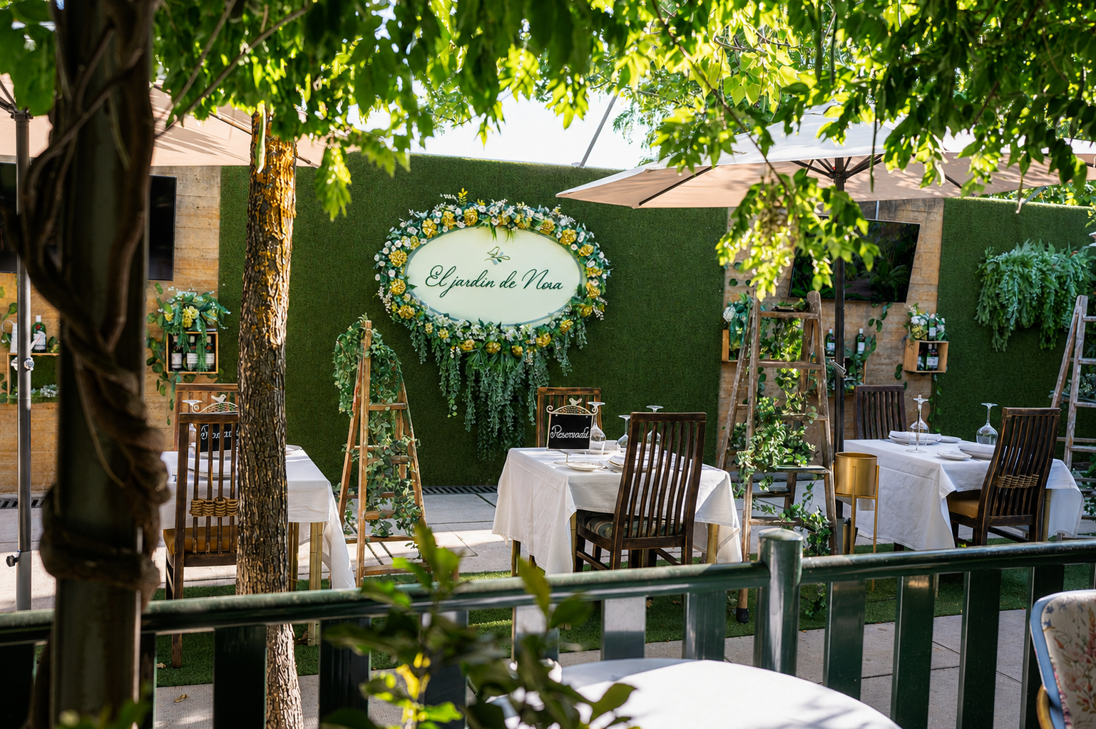 Terraza de El Jardín de Nora con mesas vestidas y el cartel del restaurante