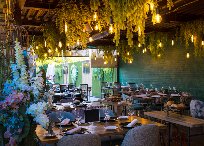 Comedor interior vestido bajo un techo de vegetación y bombillas